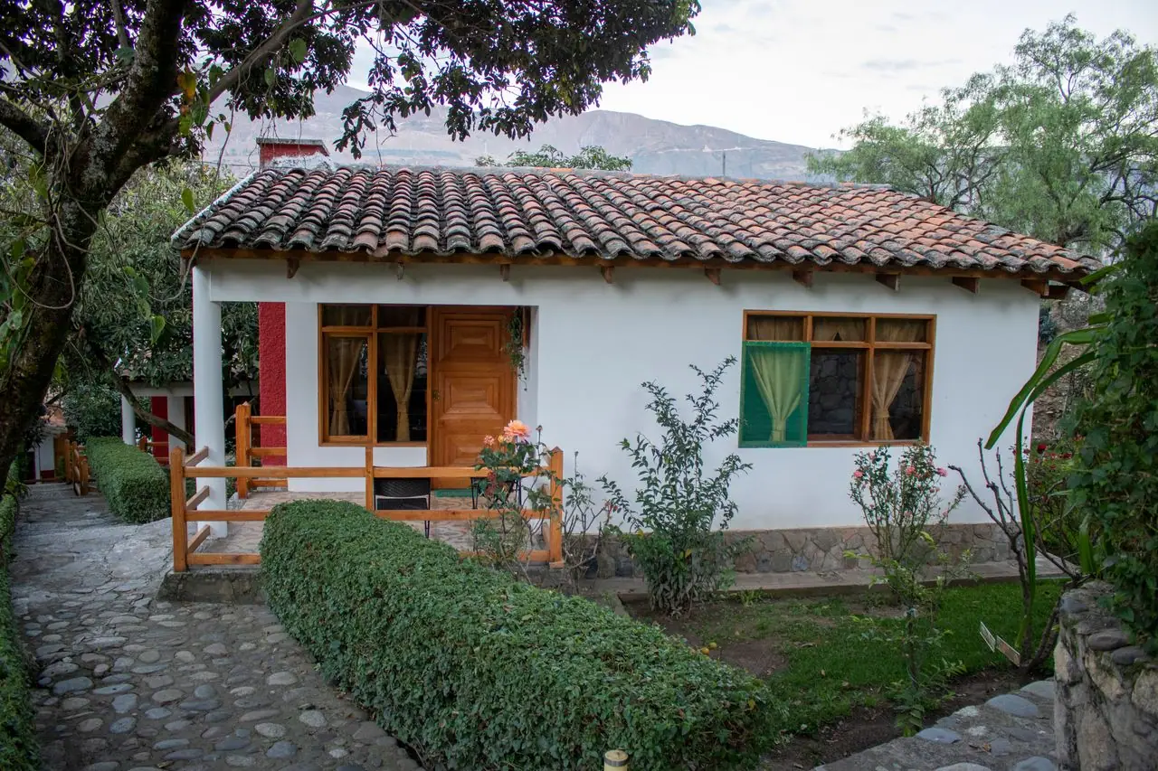 Bungalow con techo de teja y ventanas de madera junto al jardín