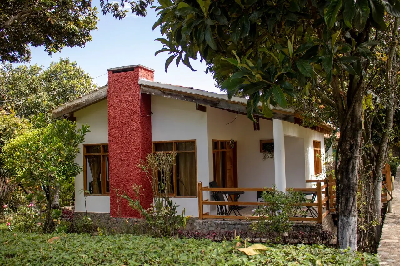 Cabaña con chimenea roja, terraza de madera y árboles frutales