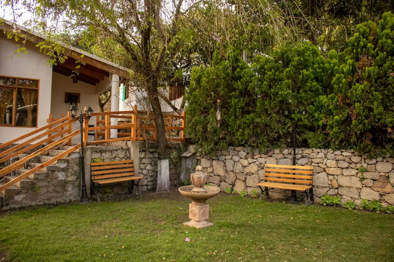 Cabaña con terraza de madera, banca y fuente de piedra