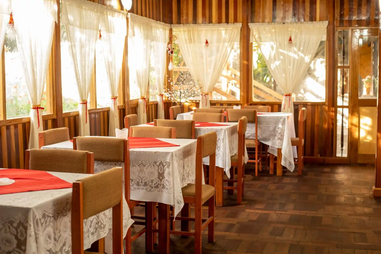 Comedor de madera con ventanales y manteles rojos