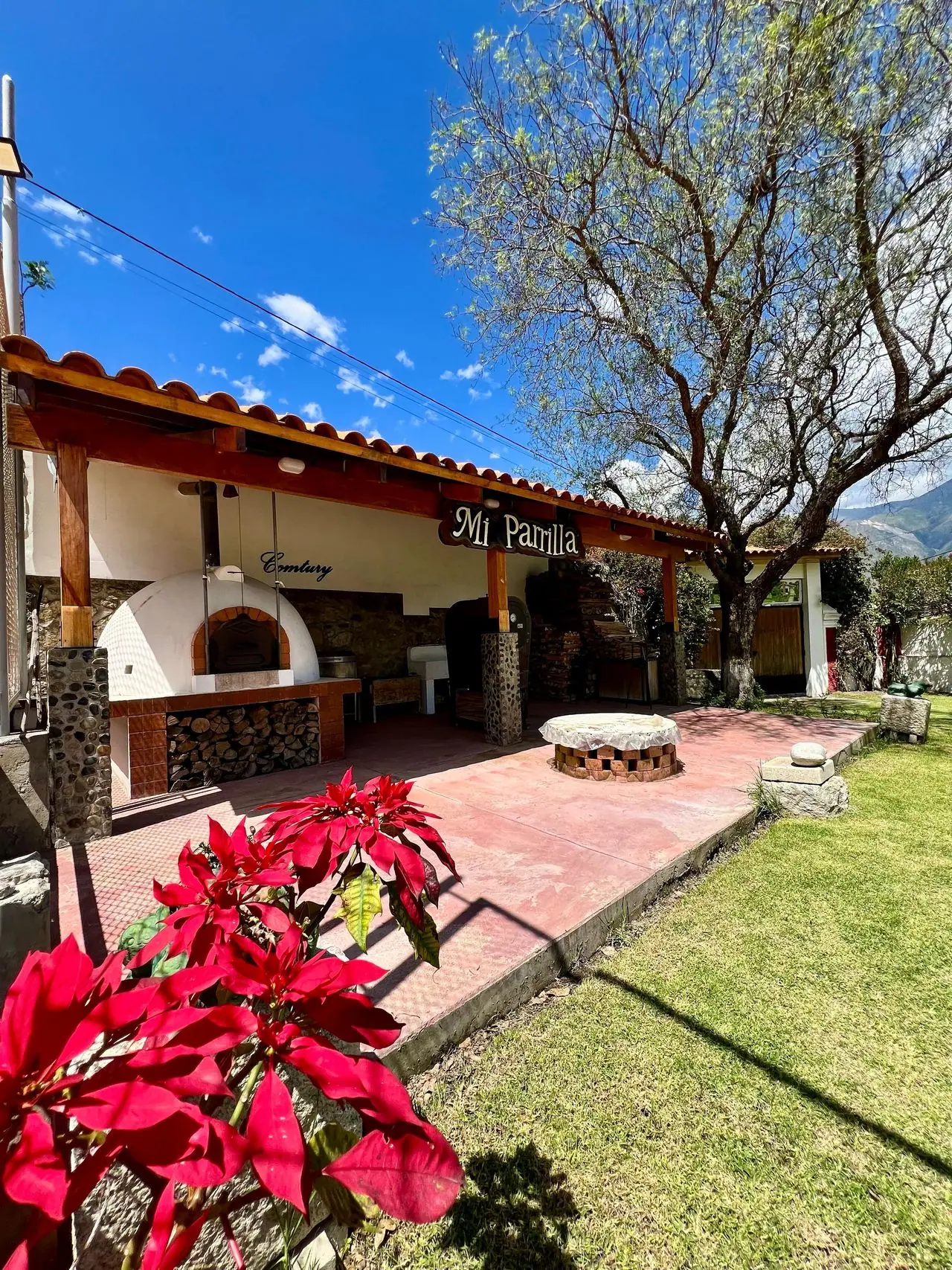 Zona de parrillas con horno de barro y flores de pascua